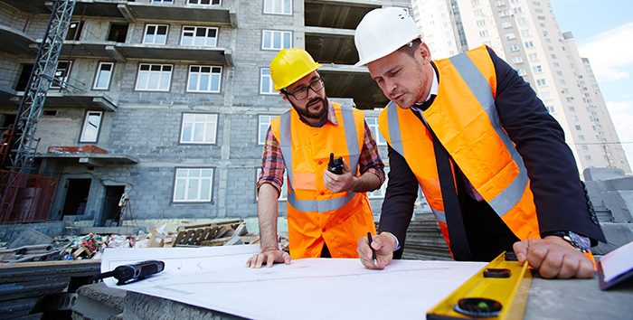 Modern engineer pointing at sketch in blueprint while explaining it to colleague
